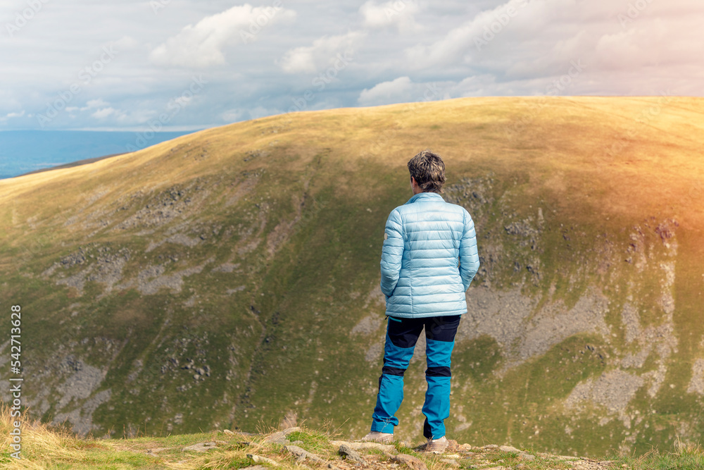 Woman reaching the destination and on the top of mountain against cloudy blue sky on autumn day Travel Lifestyle concept The national park Lake District in England