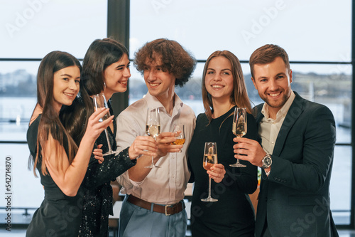 At daytime. Group of people in beautiful elegant clothes are celebrating New Year indoors together