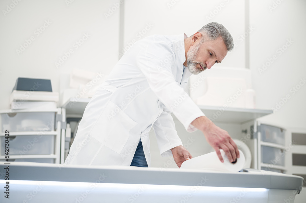 Male gray-haired doctor in a lab coat working in diagnostic center