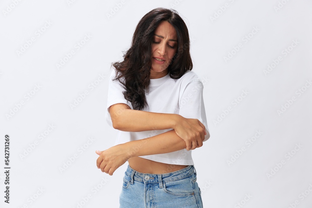 Woman pain in her arm, wrist sprain, bruised elbow in a white t-shirt on a white background, copy space Woman pain in her arm, wrist sprain, bruised elbow in a white t-shirt on a white background, copy space