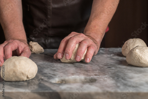 Man preparing pizza, dough on marble table.