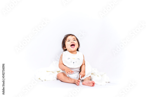 白背景の前に座り笑う1人の女の子の赤ちゃん