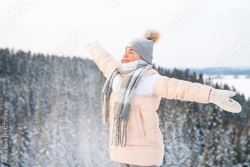 Happy woman, young relaxed carefree free man breathes deep fresh air outdoors on a winter snowy cold frosty day with arms raised, inhales frosty air in a forest or park on a natural background