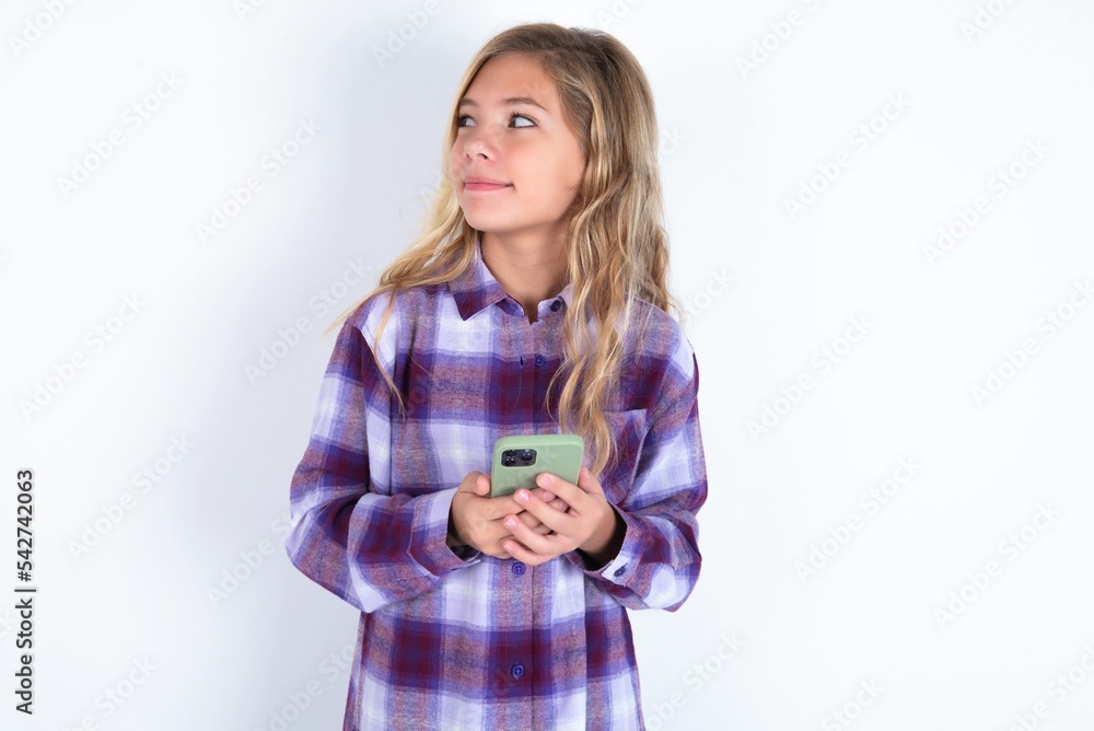 beautiful caucasian teen girl wearing plaid purple shirt over white wall holds telephone hands reads good youth news look empty space advert beautiful caucasian teen girl wearing plaid purple shirt over white wall holds telephone hands reads good youth news look empty space advert