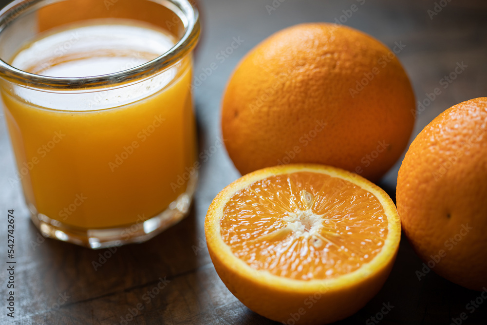 Glass of orange juice and oranges on a wooden table. Backlight. Close up Glass of orange juice and oranges on a wooden table. Backlight. Close up