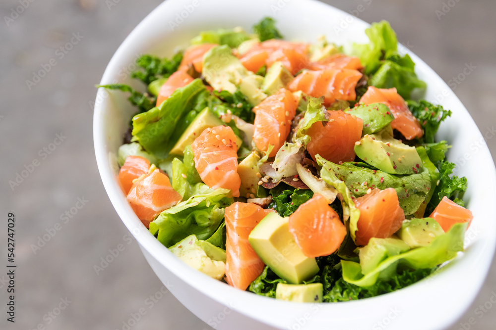 Salmon salad with green leaves and avocado on oval white bowl. Salmon salad with green leaves and avocado on oval white bowl.
