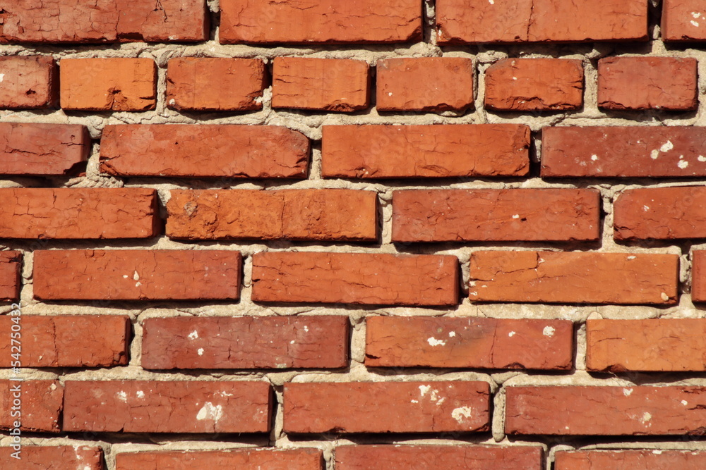 Obraz premium Close-up of a red brick wall with weathered texture and mortar joints. A classic architectural surface perfect as a background or texture element