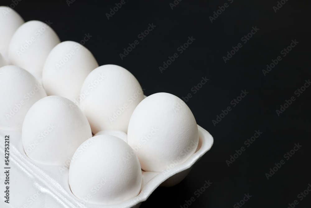 Tray with white chicken eggs on a dark background Tray with white chicken eggs on a dark background