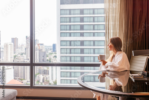 Photography Woman in bathrobe with coffee cup sitting in modern hotel or apartment