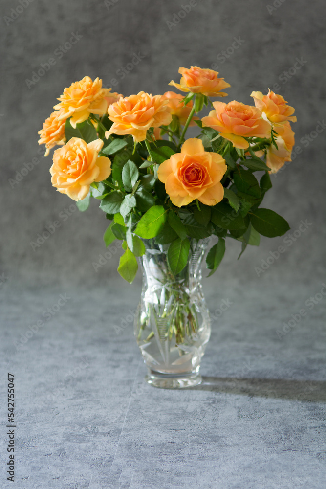 Fototapeta premium Bouquet of cream roses in a crystal vase on grey background