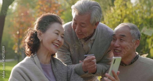 Cheerful senior Chinese adult using smart phones in the park,4K