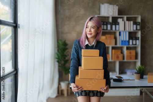 Startup small business entrepreneur of freelance Asian woman using a laptop with box Cheerful success online marketing packaging box and delivery SME idea concept © itchaznong