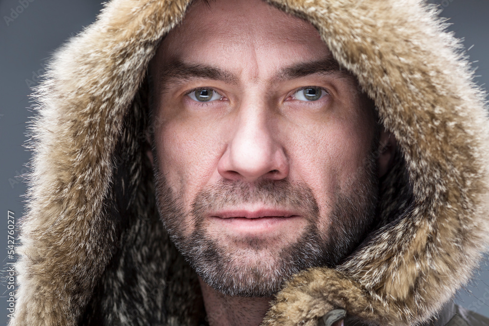 Serious brutal man in a fur hood. Close-up. Serious brutal man in a fur hood. Close-up.