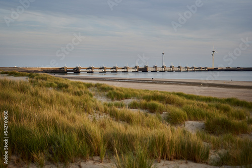 Dutch storm surge barrier (Deltawerke) on the water. Bridge with buildings for protection against high water also flood. In the evening before the beach. Netherlands, Zeeland. photo