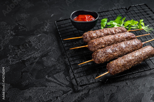 Grilled shish kebab, arabic kofta kofte kebab from mince lamb and beef meat on Skewer. Black background. Top view. Copy space photo