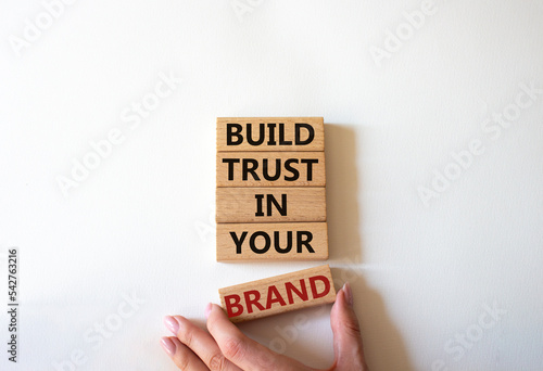 Build trust in your brand symbol. Wooden blocks with words Build trust in your brand. Beautiful white background. Businessman hand. Business and Build trust in your brand concept. Copy space.