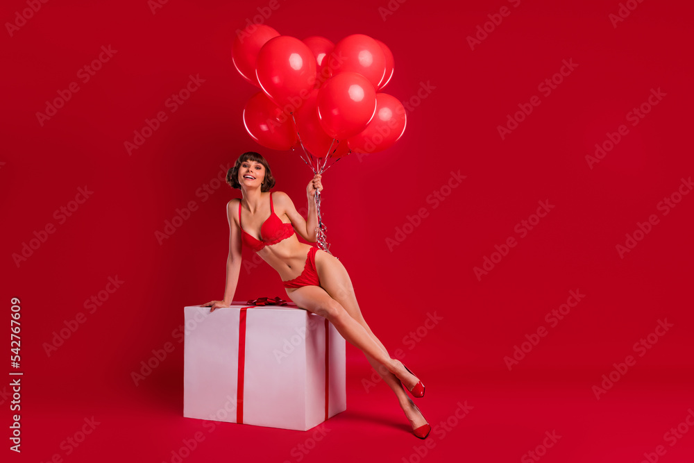 Full length photo of gorgeous pretty lady sit large package hold air balls mall open podium isolated shine color background Full length photo of gorgeous pretty lady sit large package hold air balls mall open podium isolated shine color background