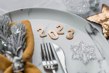 Table setting. A marble plate with a rabbit on a napkin, branches of a Christmas tree and Christmas decorations on a gray background. The concept of Merry Christmas, New year 2023 and restaurants.