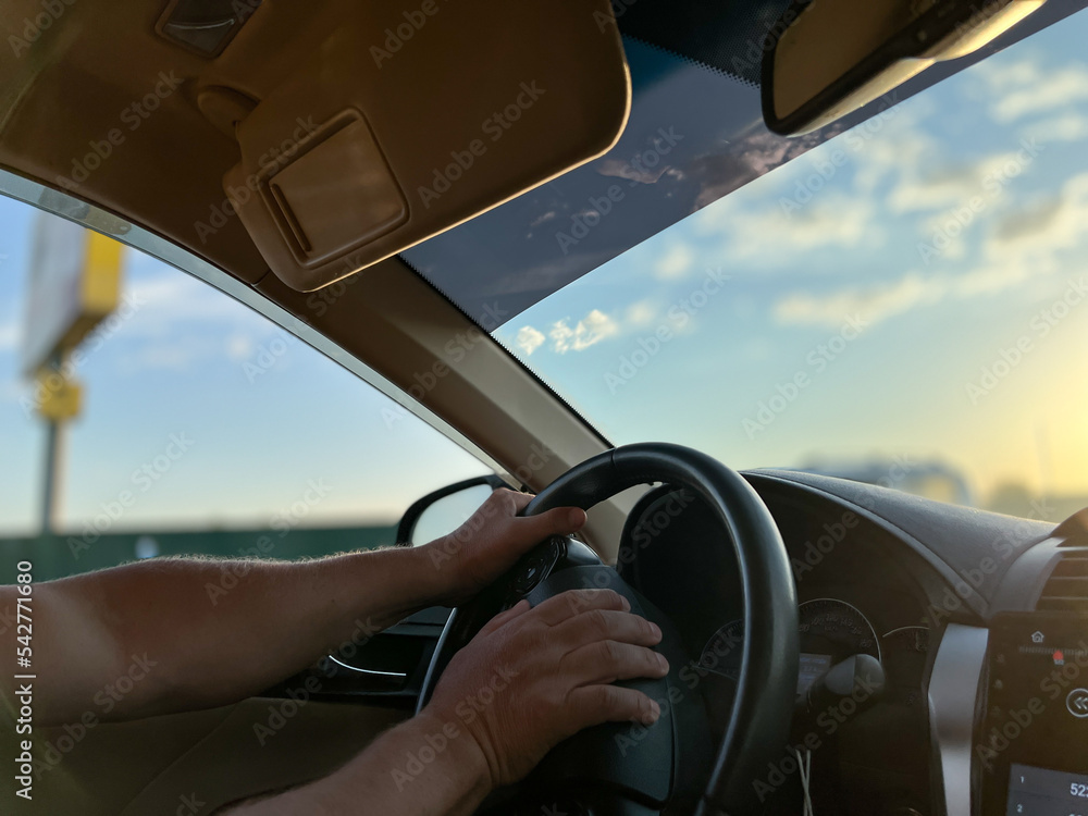 A man drives a car with his hands on the steering wheel. Road trip, the concept of traveling by car.
