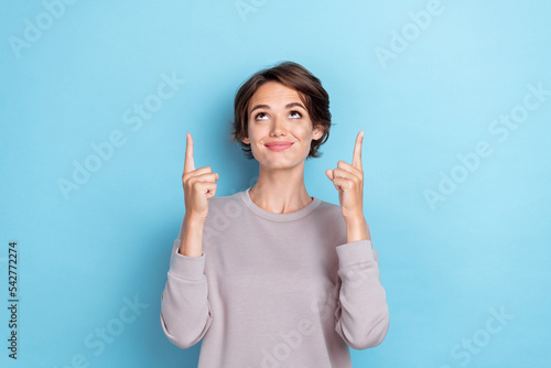 Photo of optimistic cheerful girl short hairstyle wear gray sweatshirt indicating looking at empty space isolated on blue color background