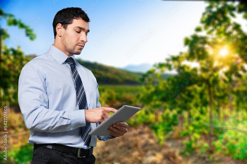 Thinking young farmer hold digital tablet on farm background.