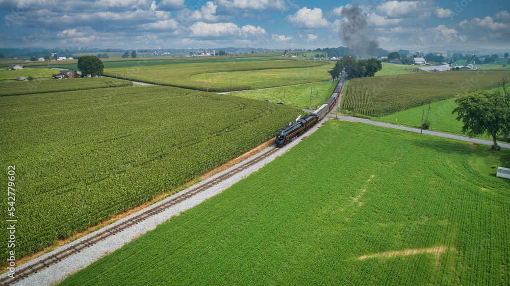 Drone View of an Antique Steam Engine, Approaching, Blowing Steam and Traveling Along the Countryside on a Sunny Day