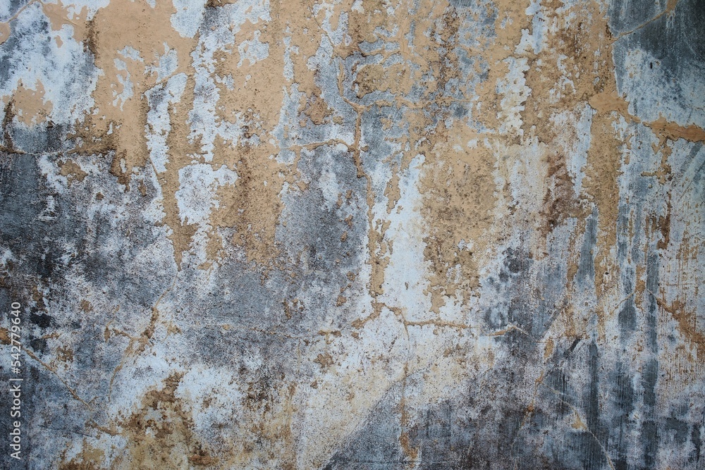 Naklejka premium A weathered concrete wall with cracks and peeling paint, showing signs of age and decay.