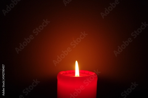 A red candle on a dark background, emphasizing the flame