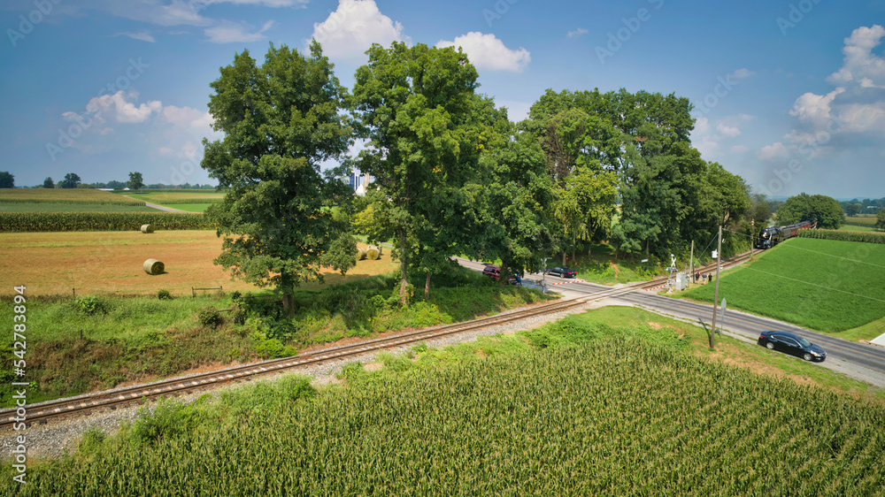 Drone View of a Steam Passenger Train Approaching A Crossing in a Farmland Countryside on a Sunny Summer Day