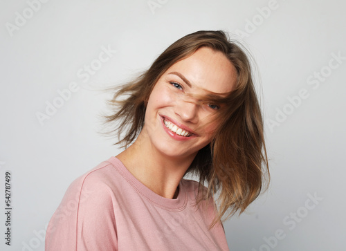 Cheerful happy young beautiful blond woman looking at camera smiling laughing over grey background.