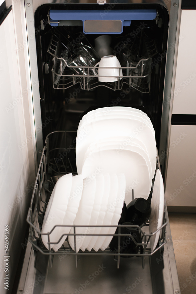 Open dishwasher with white and black clean dishes after washing in the
