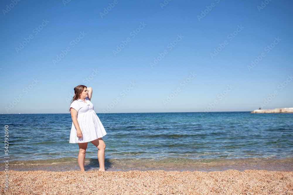 Beautiful plus size woman walking in the beach, resting and enjoy the moment to be alone and meditate near the sea or ocean in the beach. Overweight woman wearing dress