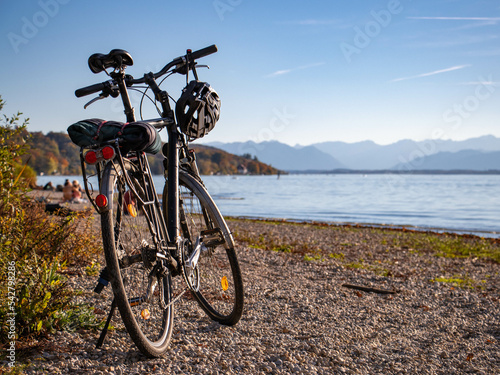 Fototapeta Naklejka Na Ścianę i Meble -  Bike parked on a pebble beach by the lake Starnberg, Bavaria, Germany with mountains in the background