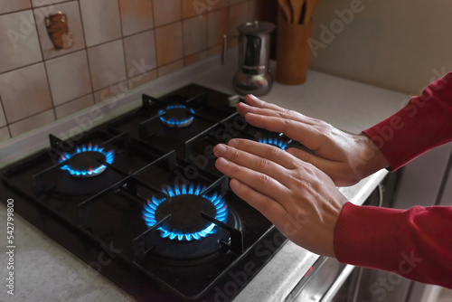 Hands of a man near a gas stove in close-up. Cold heating season