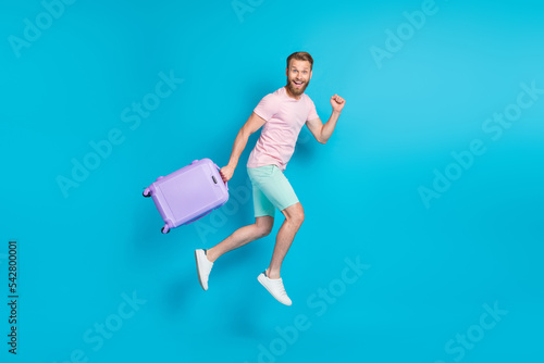 Full body photo of attractive young guy excited running jumping departure dressed stylish pink look isolated on aquamarine color background