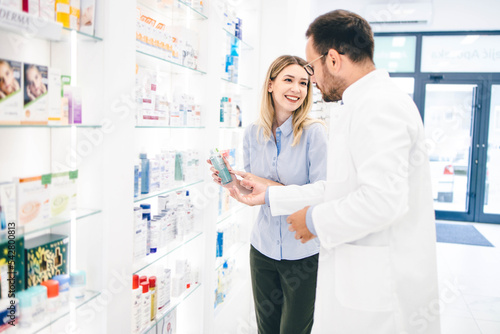 Young man working in pharmacy Helping his client to pick up best products Pharmacist recomending products