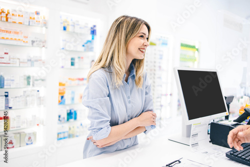 Young woman in phamracy store, looking to by some healthy suplements. Pharmacy worker is helping her