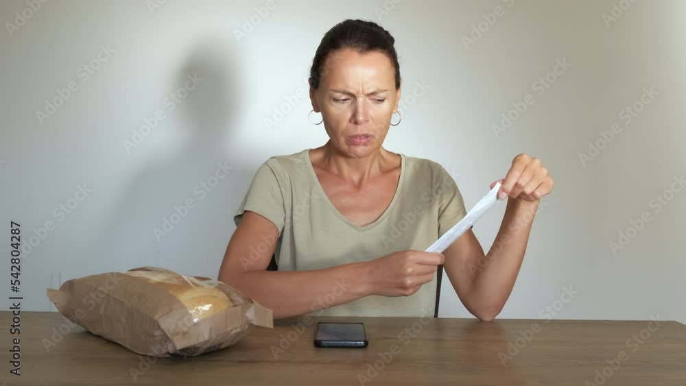 Female expense food tracking. A stressed housewife check a bill for expense food from supermarket. A concept of expense food tracking and economical crisis in the world. Female expense food tracking. A stressed housewife check a bill for expense food from supermarket. A concept of expense food tracking and economical crisis in the world.