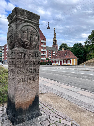 Historic stone milestone marker by the side of road with Our Saviour's Church (Vor Frelsers Kirke) in distance, Christianshavn, Copenhagen, Zealand, Denmark photo