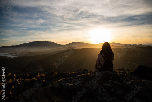 Beautiful women sitting on a rock during sunset on the mountains