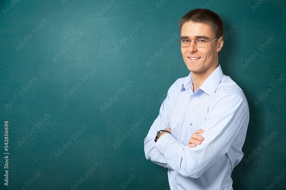 Happy young male teacher posing on blackboard background Happy young male teacher posing on blackboard background