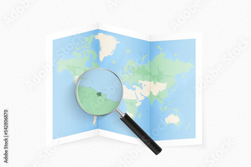 Enlarge Suriname with a magnifying glass on a folded map of the world.