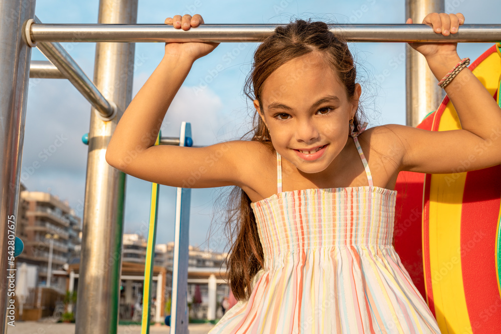 Little cute child girl in playground on the beach with smile on summer