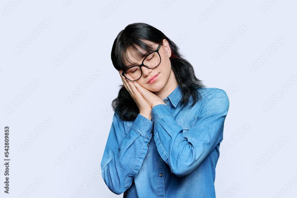Young woman sleeping with closed eyes, on white studio background