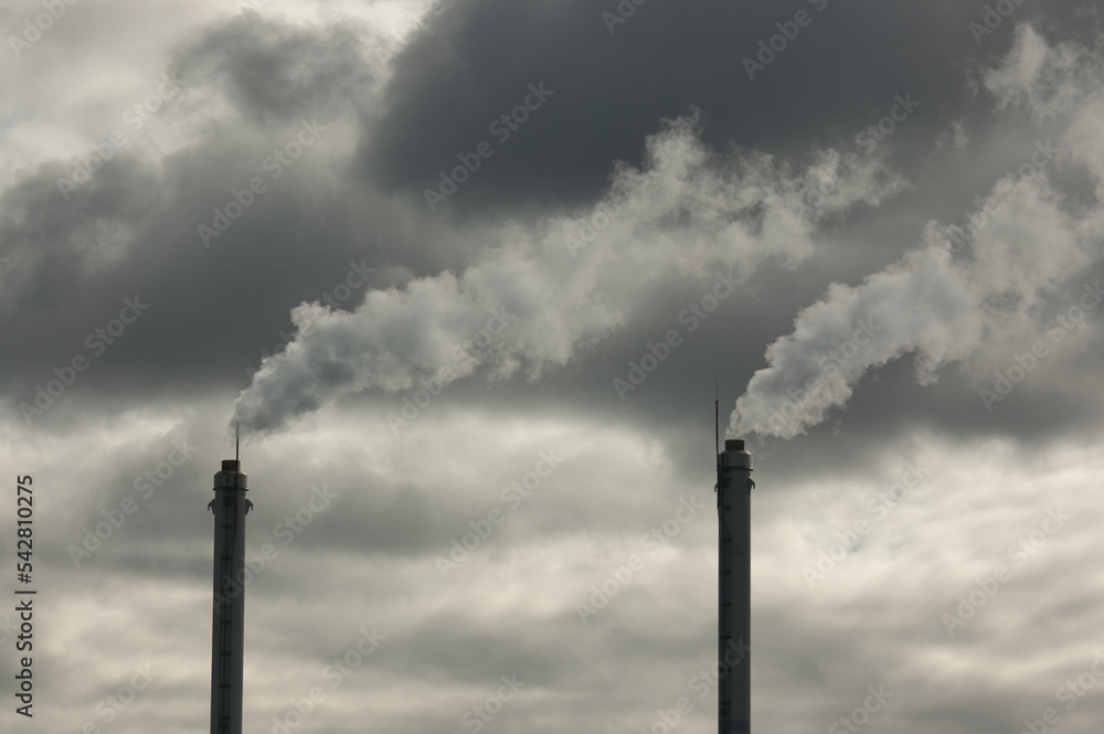 metal pipes of the plant against a gray sky, gray smoke comes out of the pipes metal pipes of the plant against a gray sky, gray smoke comes out of the pipes