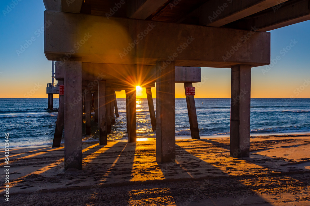 Sunrise over the ocean seen from under the pier