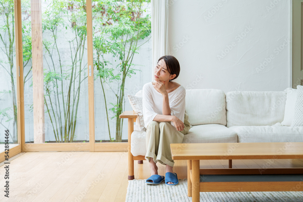 リビングで考え事をする主婦 リビングで考え事をする主婦