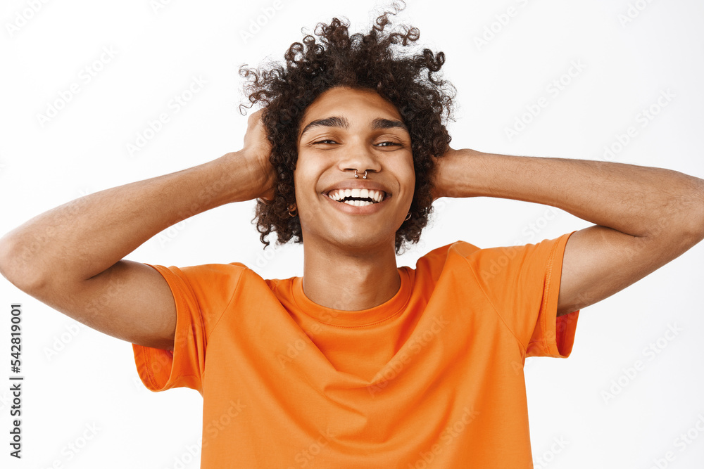 Close up of handsome hispanic boy, guy showing his curly healthy, natural hair, touching haircut and smiling, standing over white background Close up of handsome hispanic boy, guy showing his curly healthy, natural hair, touching haircut and smiling, standing over white background