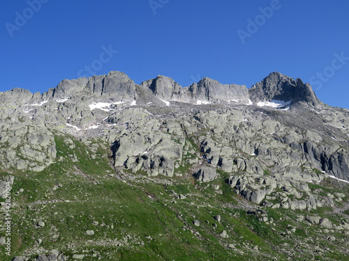 Alpine rocky peak Pizzo della Valletta (2726 m) above the reservoir lake Lago di Lucendro in the Swiss mountain area of St. Gotthard Pass (Gotthardpass), Airolo - Canton of Ticino (Tessin) Switzerland photo