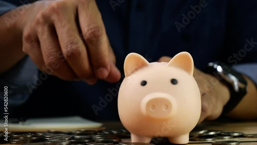 4K-UHD Slow motion of man hand insert coins in pink piggy bank and writing for account save money. Planning step up, saving money for future plan, retirement fund. Business investment-finance.